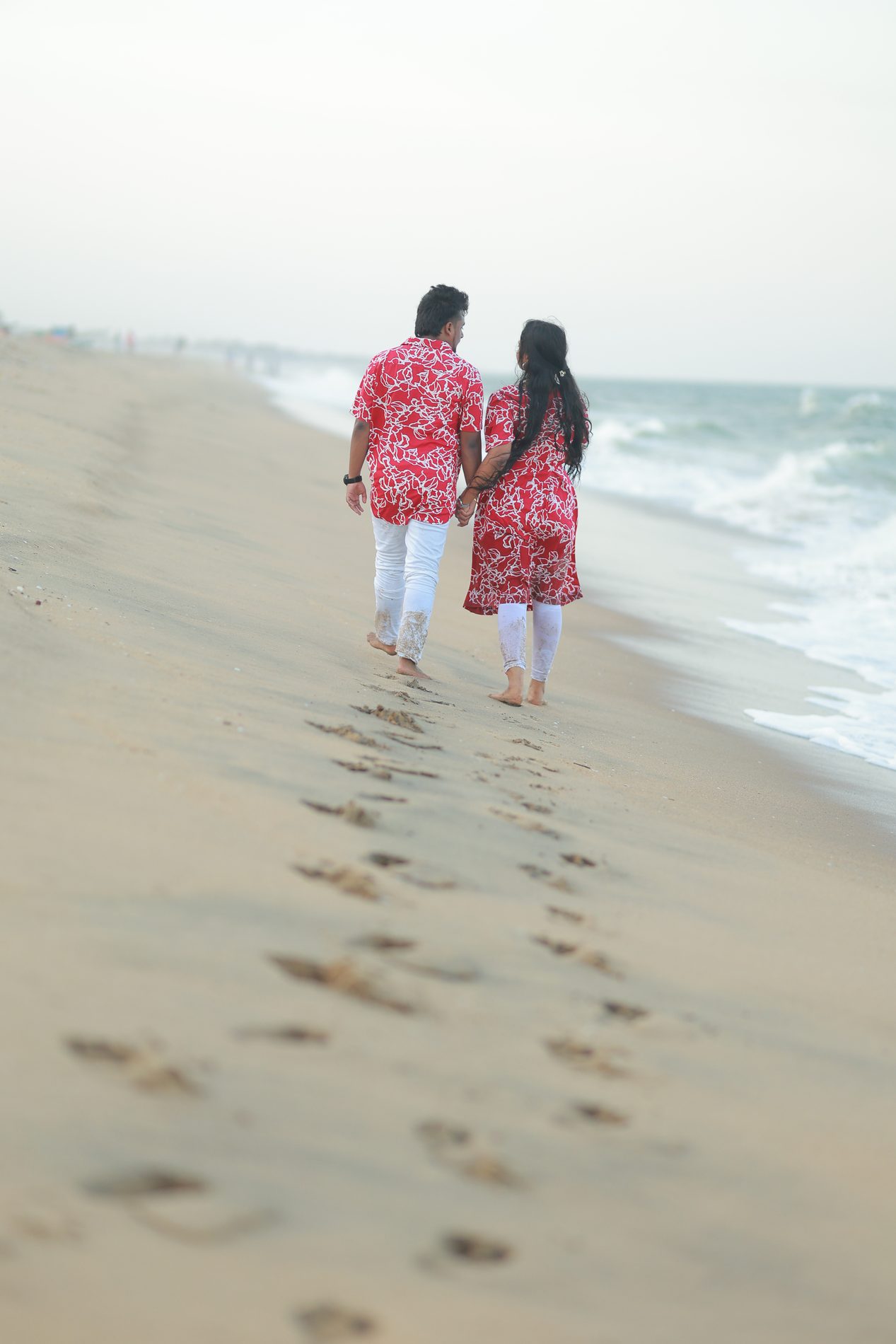 Two sets of footprints trailing down an empty beach