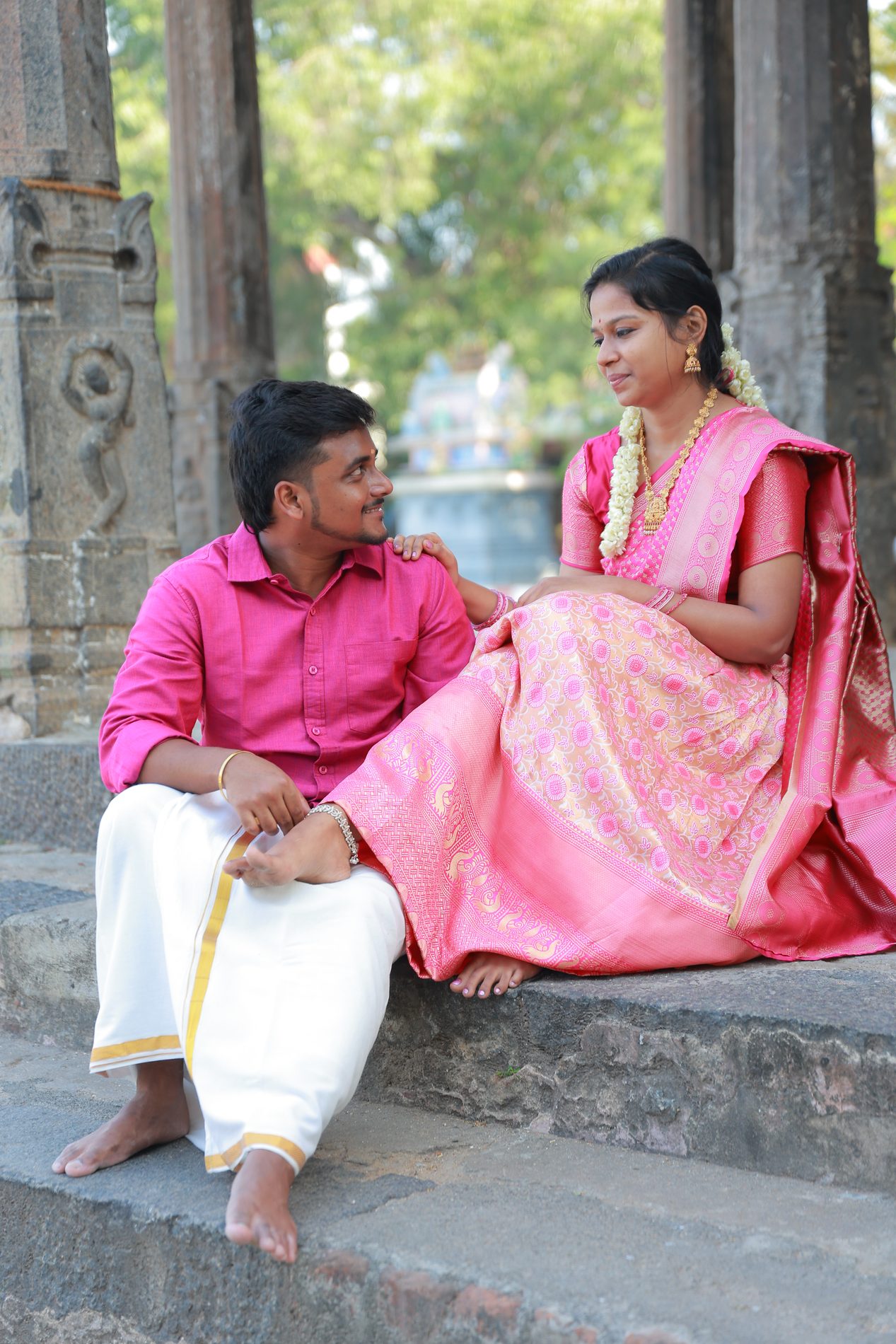 Venkatesh and Brindha leaning close together at the temple, soft afternoon light
