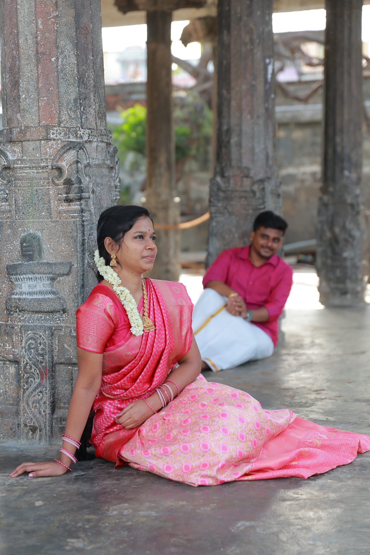 Venkatesh and Brindha seated together among ancient temple pillars
